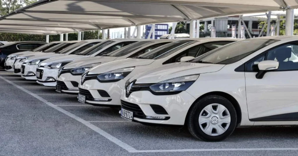 A row of identical white rental cars parked under a covered parking area.