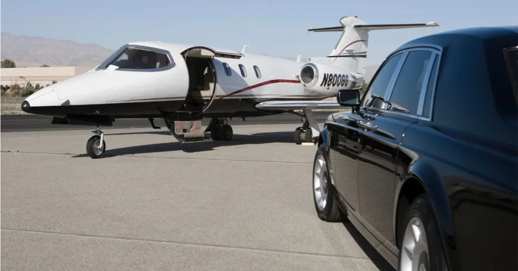 A private jet parked on an airport runway with its door open, while a black luxury car is positioned in the foreground.